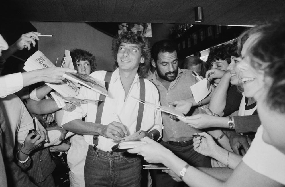 Manilow signs his autograph for fans in the U.K. in 1983.