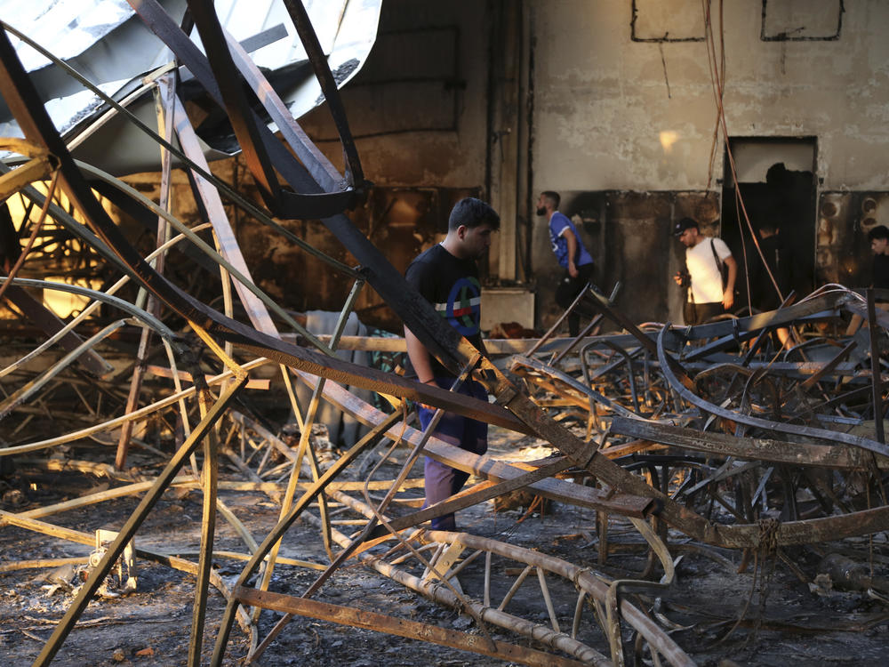 People gather at the site of a fatal fire, in the district of Hamdaniya, Nineveh province, Iraq, on Wednesday, Sept. 27, 2023.
