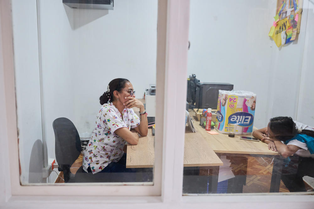 An employee at Casa, sits with Livia as they call her family in the wake of her uncle's death. Livia plans to return to Venezuela in September and be reunited her daughter.