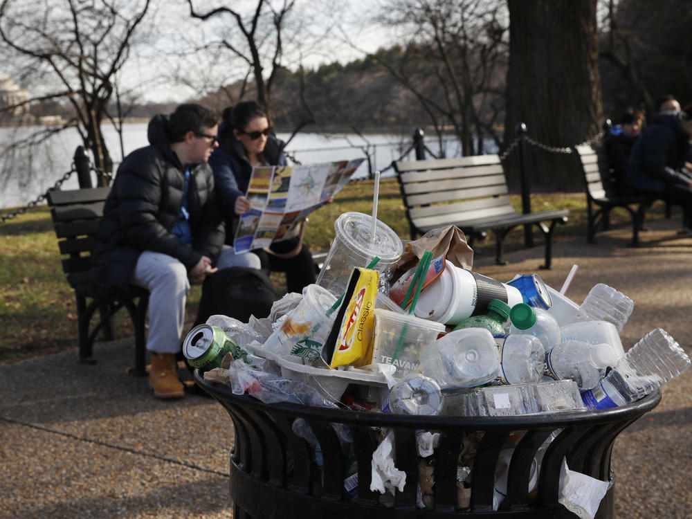 In this file photo, a trash can overflows as people sit outside of the Martin Luther King Jr. Memorial on Dec. 27, 2018, in Washington, during a partial government shutdown. The D.C. government cleaned up overflowing trash in the area, controlled by the Dept. of Interior as National Park land.