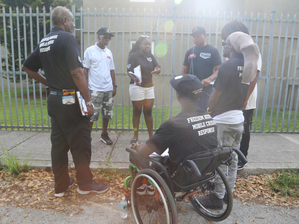 Peacemakers have a debrief before concluding their work for the day at the Lincoln Fields apartments complex in Miami, Fla. Lamont Nanton (second from left) is the group's manager and Shameka Pierce (third from left) works with the group.