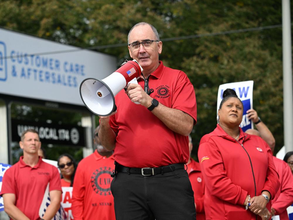 UAW President Shawn Fain addresses picketing union members at a GM Service Parts Operations plant in Belleville, Mich., on Sept. 26, 2023. The Big Three automakers are pleading the union to tone down its language, with Stellantis saying the two sides are not at war.