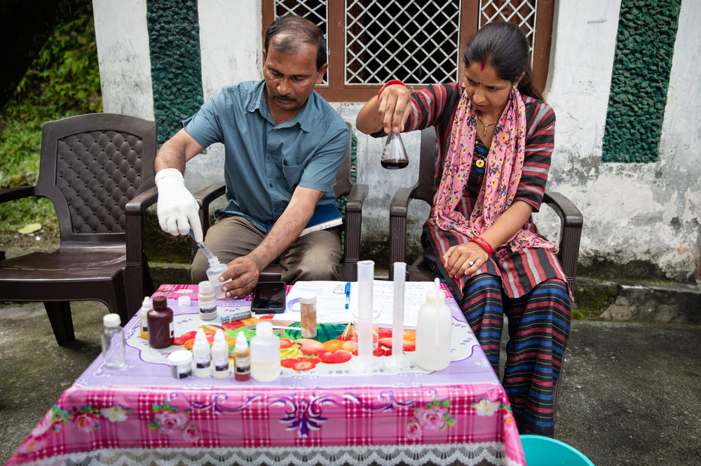 Villager Manju Palariya and Harish Palariya, who is part of a technical team advising the area on how to refresh springs, use the testing kit provided by the Central Himalayan Rural Action Group to test the water from the spring near her house. They test for a variety of matters, from chloride levels to fecal matter contamination.