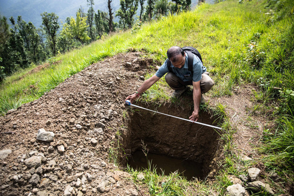 Harish Palariya, a technical adviser to help with keeping springs full of water, measures the width of a percolation pit, designed to let rainwater collect and seep into the ground.