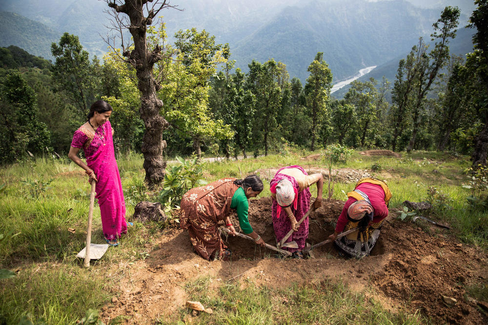 The women of Raushil village's water committee dig a percolation pit, which provides a place for rainwater to accumulate and then seep into the ground during heavy downpours.