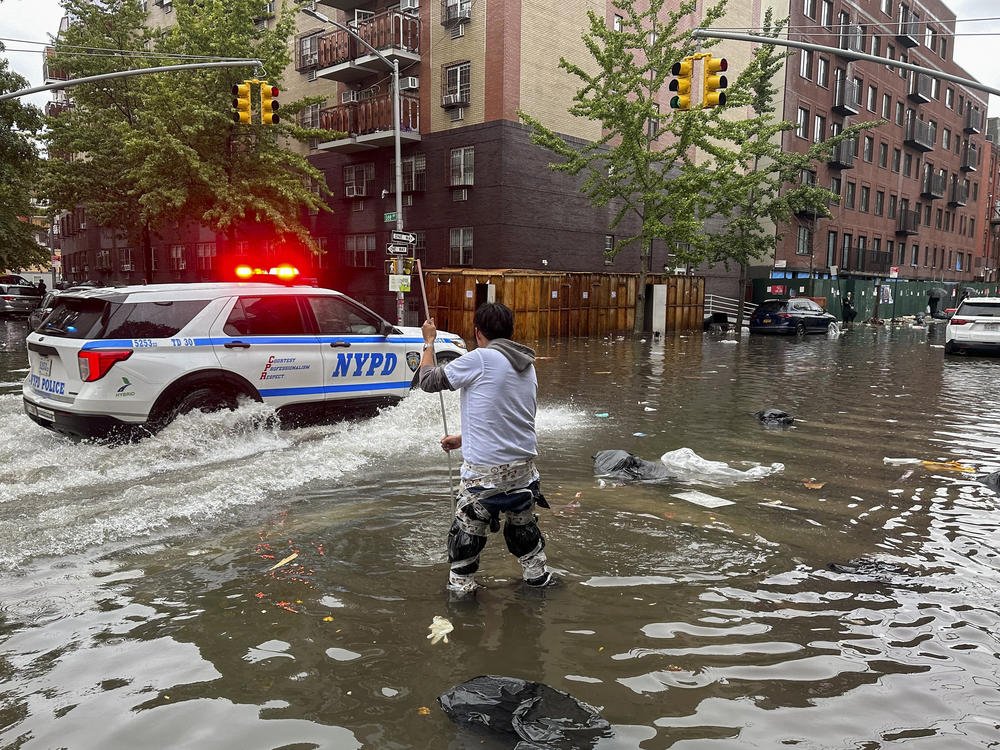 A man works to clear a drain in flood waters, Friday, Sept. 29, 2023, in the Brooklyn borough of New York.