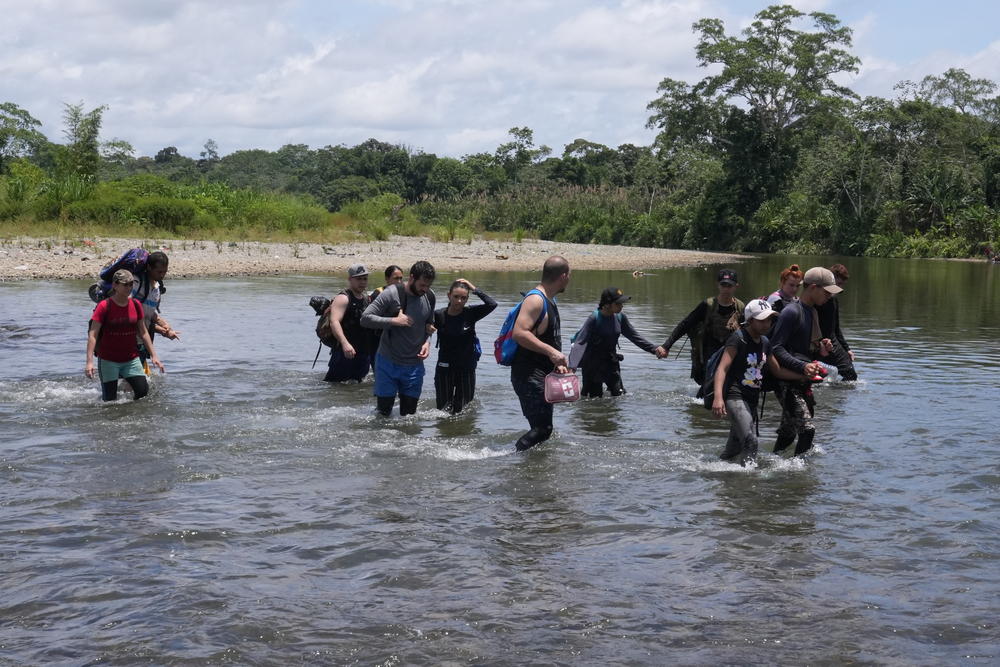 A group of migrants trudges across the Turquesa River in Panama, as they approach the village of Bajo Chiquito. The trek across the jungle can take anywhere from three to seven days, depending on the weather and the route they take.