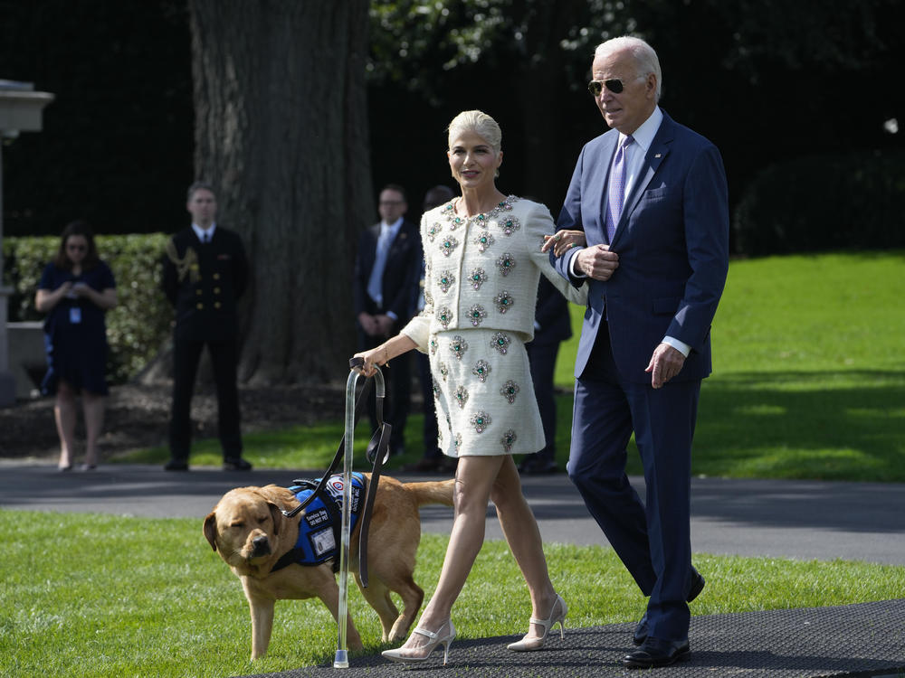 President Joe Biden walks with actress Selma Blair and Blair's service dog Scout as they arrive for an event to celebrate the Americans with Disabilities Act on the South Lawn of the White House on Monday.