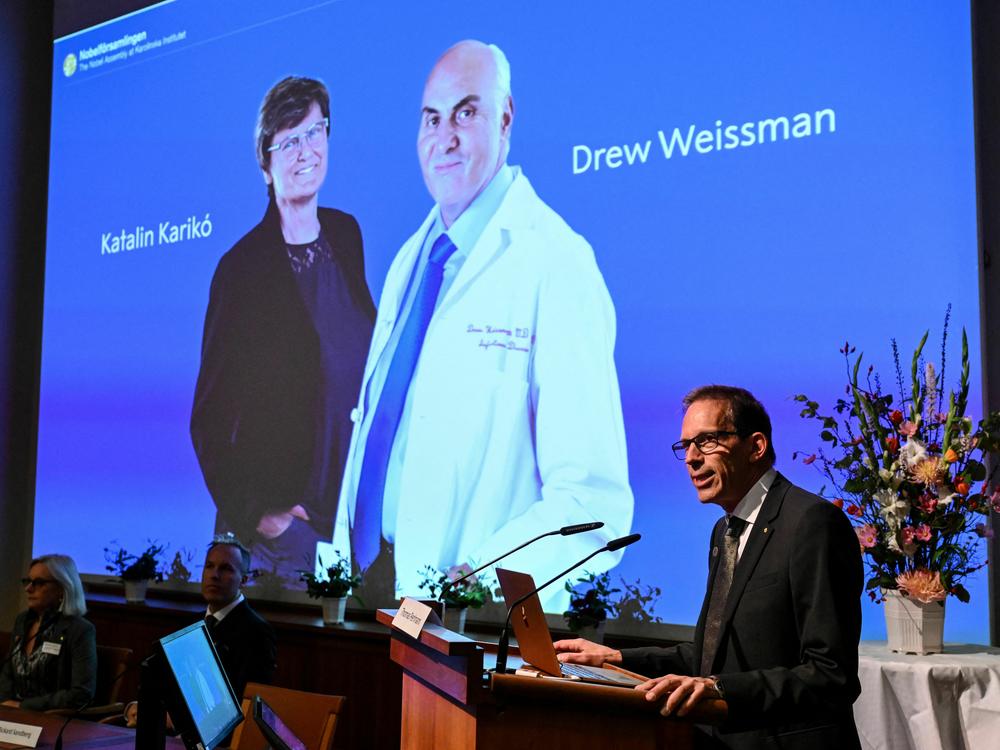 Secretary-General of the Nobel Assembly Thomas Perlmann speaks in front of a picture of Katalin Karikó and Drew Weissman, winners of the 2023 Nobel Prize in Physiology or Medicine, at the Karolinska Institute in Stockholm on Monday.