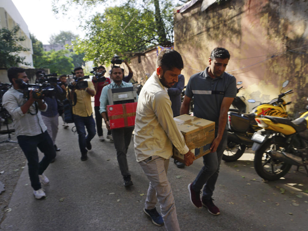 Security officers carry boxes of material confiscated after a raid at the office of NewsClick in New Delhi, India, Tuesday. Indian police raided the offices of the news website as well as the homes of several of its journalists, in what critics described as an attack on one of India's few remaining independent news outlets.