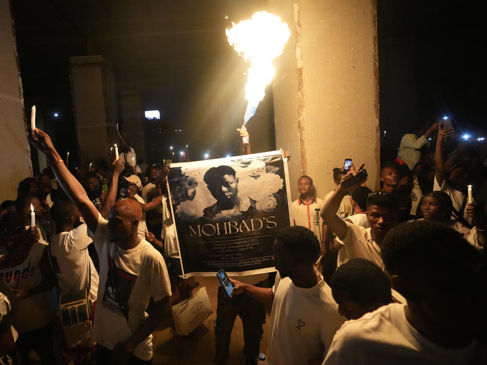 People hold candles and a flare during a protest at a park in Lagos, Nigeria, on Sept. 21, to demand justice after Mohbad's death.