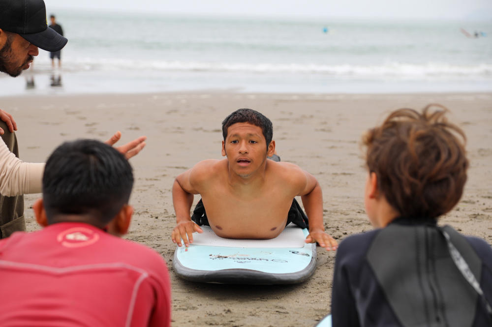 Instructor Oliver Asencio Lynes is teaching students how to stand up on a board. In the photo, he's in the starting position.