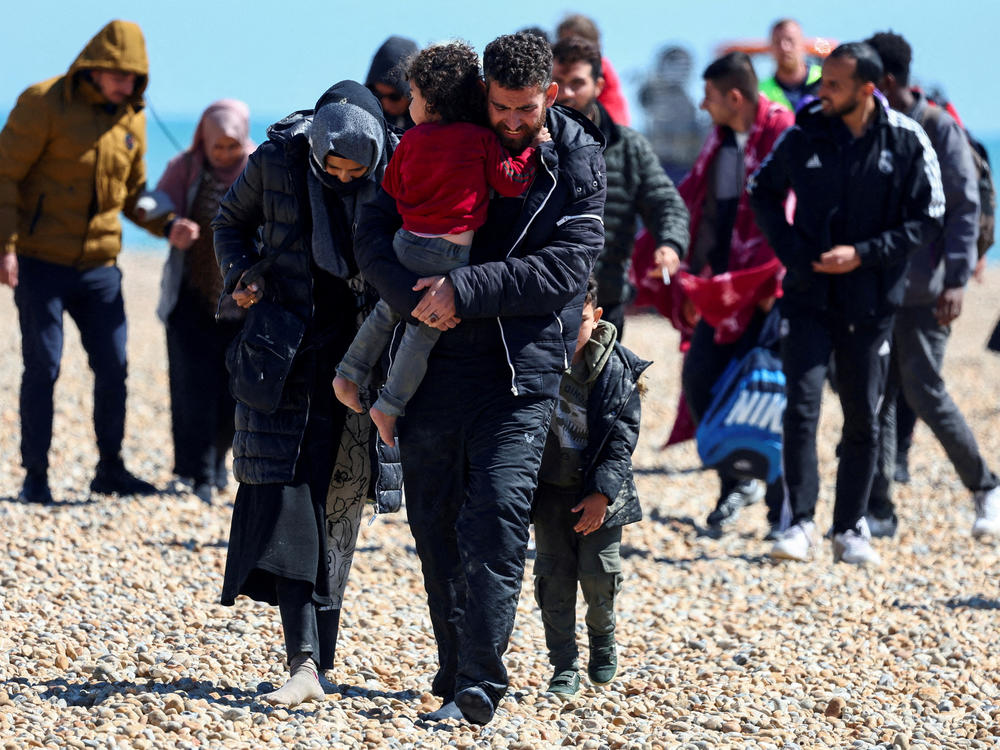 People believed to be migrants walk in Dungeness, a headland on the coast of England, on Aug. 16.