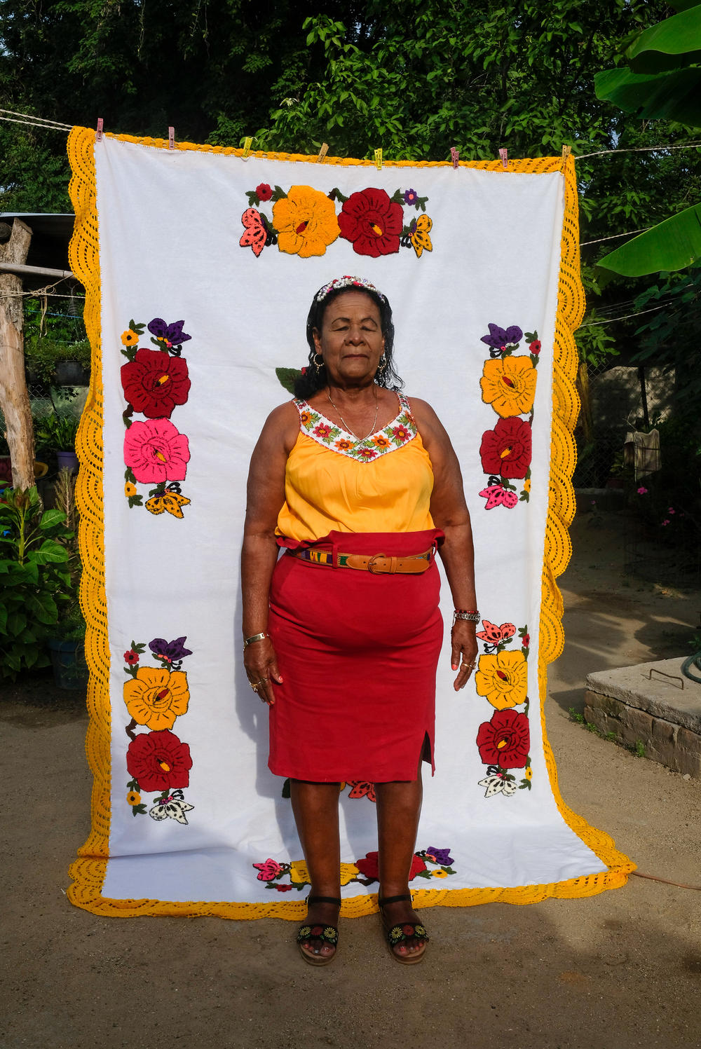 Tomasa Noyola, a leader in San Nicolás, in her garden on a background of one of the many textile handmade pieces crocheted by her.