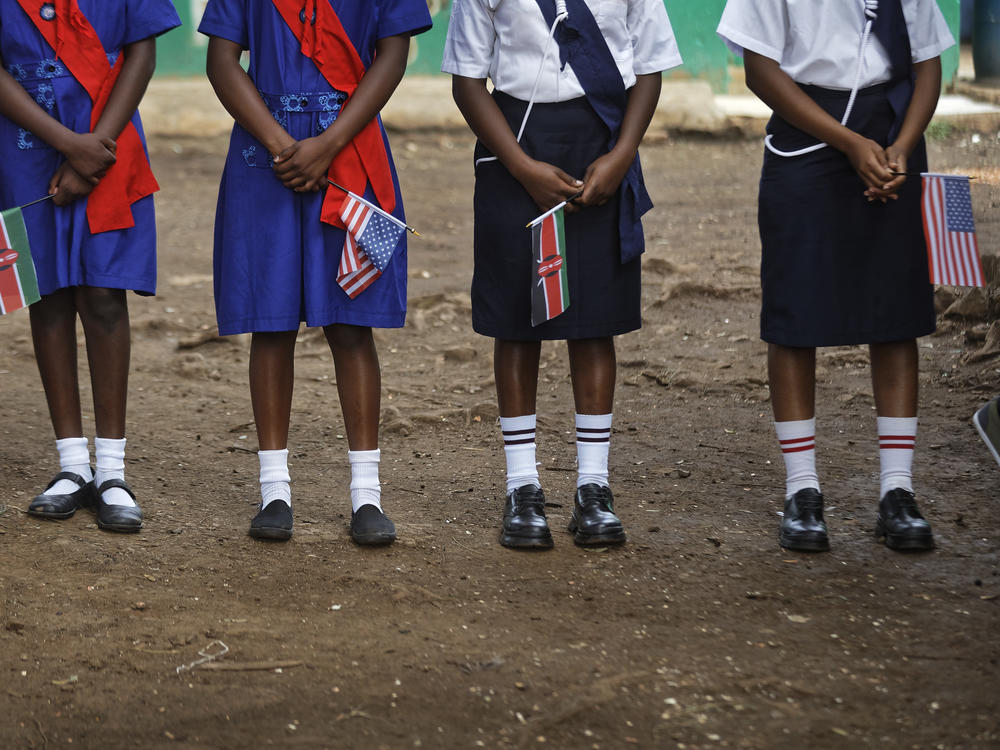 Girls hold U.S. and Kenyan flags while waiting for the arrival of a U.S. ambassador at a site supported by PEPFAR in Nairobi, Kenya in March 2018.