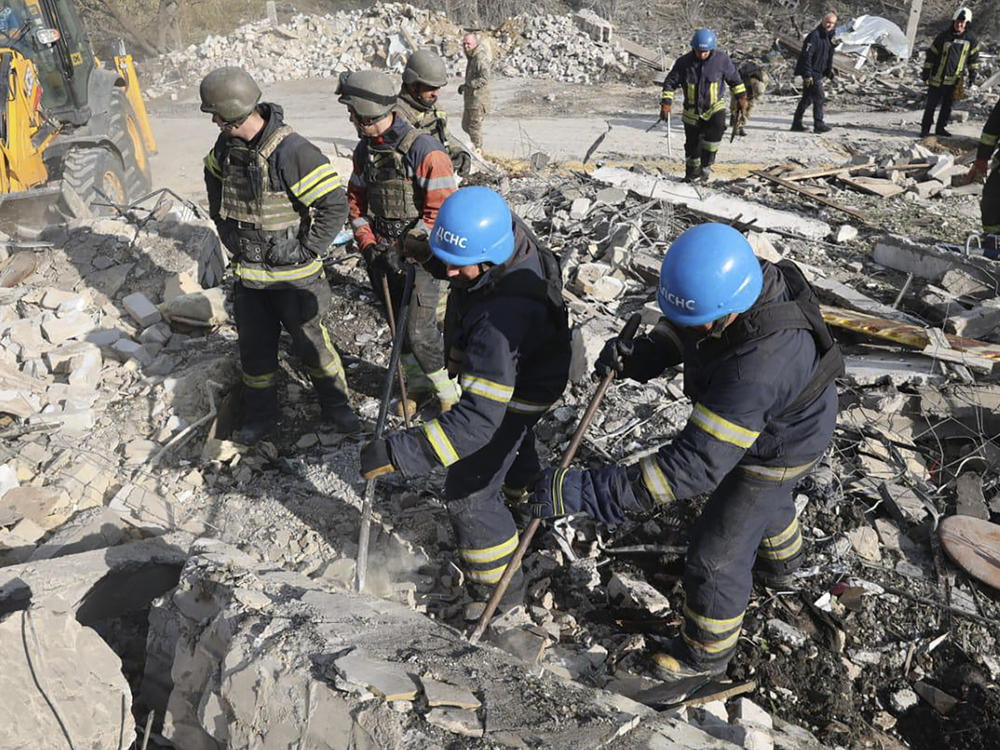 In this photo provided by the Ukrainian Presidential Press Office, emergency workers search the victims of the deadly Russian rocket attack that killed dozens of people in the village of Hroza near Kharkiv, Ukraine, Thursday, Oct. 5, 2023.