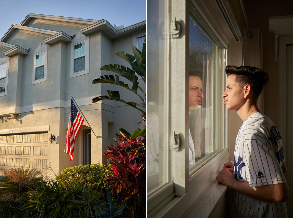 A U.S. flag hangs on the wall of a house in Tampa, Florida. Yossell Machado Fígueredo, 21, looks out the window of his room. Like most Cubans in recent years, Yossell arrived at the southern border through a journey with his mother and sister by land from Nicaragua.