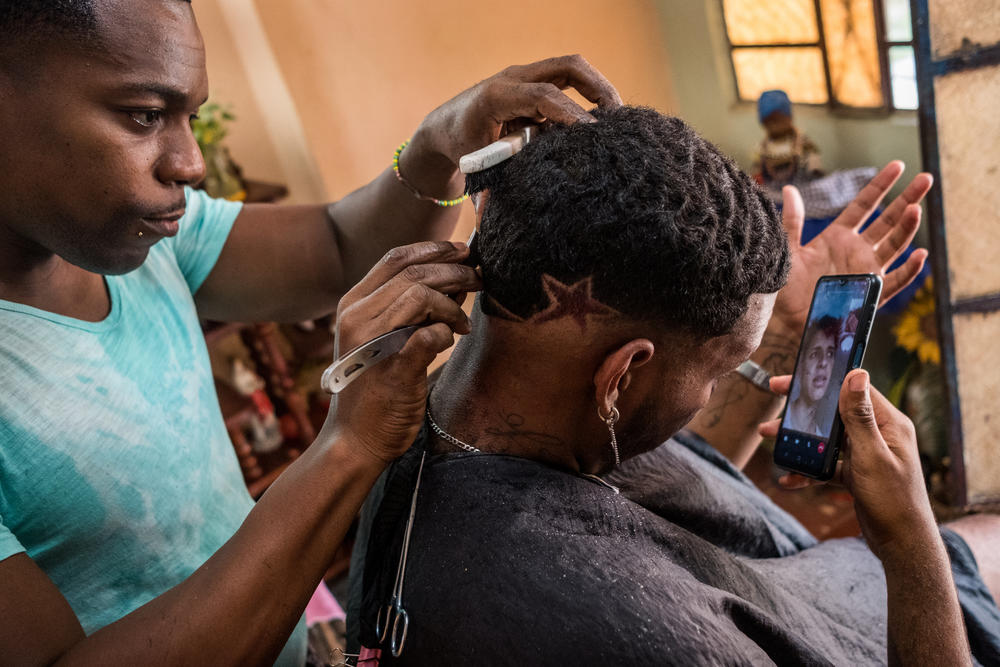 Gabriel has his hair cut in barrio Los Pocitos in Havana. He calls Yossell, his best friend, every day. He misses him terribly. For himself he hardly sees a future in Cuba, but without money, he has no possibility to migrate.