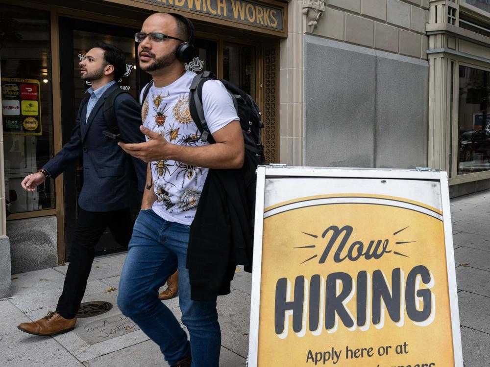 People walk past a restaurant, with a hiring sign outside in Washington, D.C., on Oct. 5, 2023. Employers added 336,000 jobs in September, far more than what analysts had predicted.