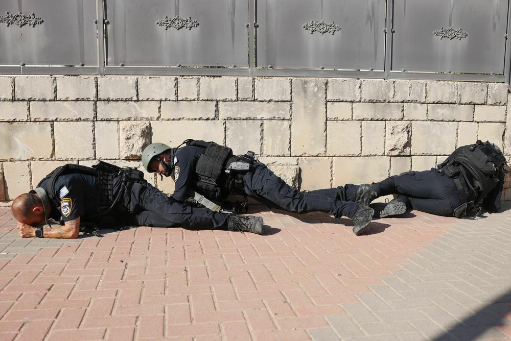 Sat., Oct. 7: Members of the Israeli frorces take cover on the side of a street in Ashkelon as sirens wail while barrages of rockets are fired from the Gaza Strip into Israel.