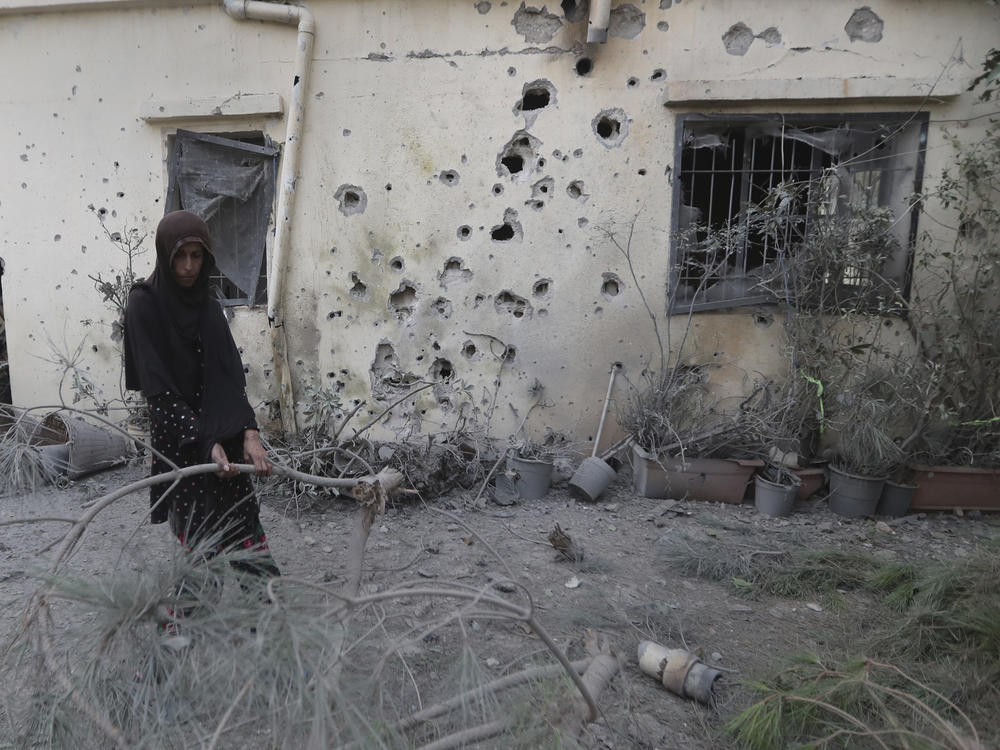 A Lebanese woman removes broken tree branches after her house was hit by Israeli shelling, in Dahaira village, South Lebanon, Monday.