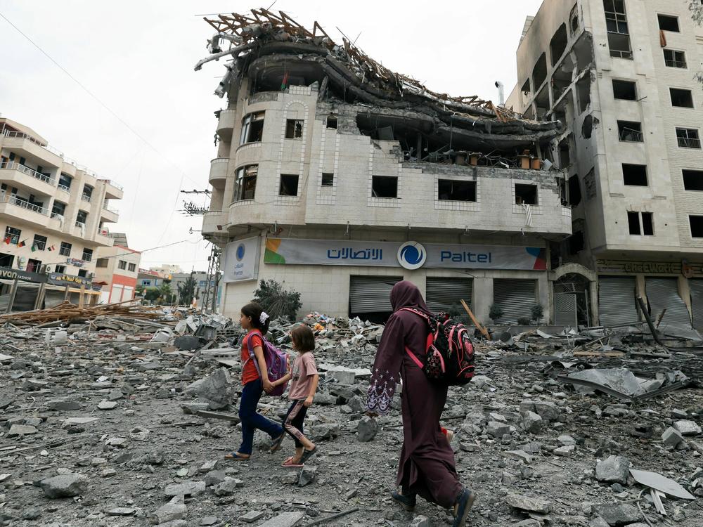 Palestinians walk through debris amid massive destruction from Israeli airstrikes in Gaza City's al-Rimal district, on Tuesday, Oct. 10, 2023.