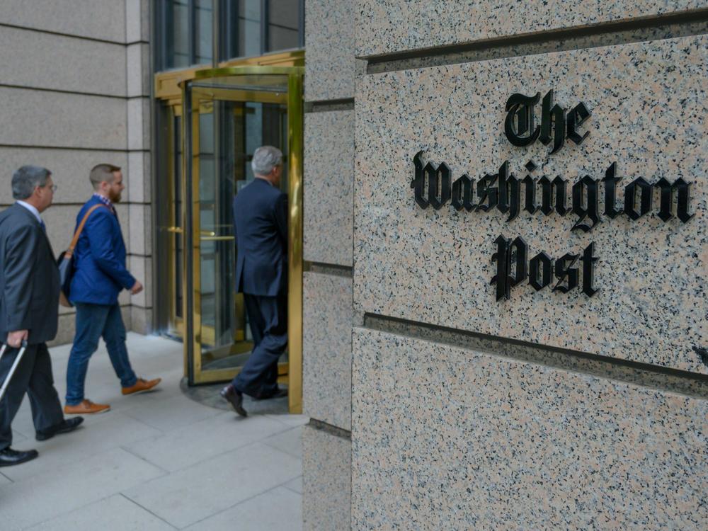 People enter The Washington Post's headquarters. The newspaper is cutting nearly 10% of its jobs through voluntary buyouts.