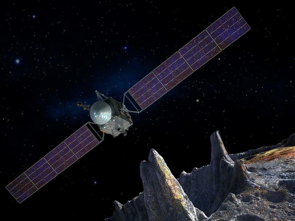 An artist's conception of the Psyche spacecraft approaching an asteroid that's largely composed of metal.