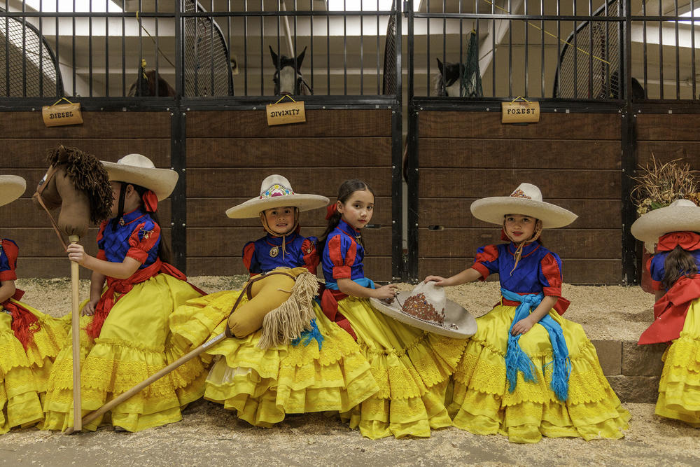 Sophia Barragan, Bethany Diaz and Isabel Moreno Jacobo, members of the Escaramuzitas Adelitas de Colorado, pose for a photo while they wait to perform with the stick horses at the National Western Stock Show's Mexican Rodeo Extravaganza.
