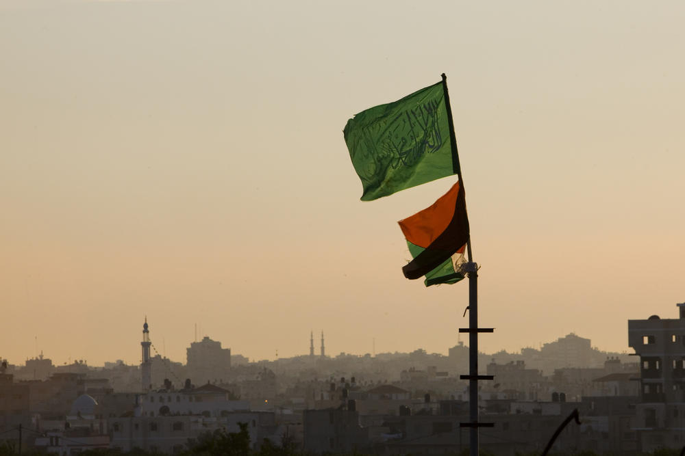 A Hamas flag, top, and a Palestinian flag fly at sundown in the Jabalia refugee camp, northern Gaza Strip, April 15, 2010.