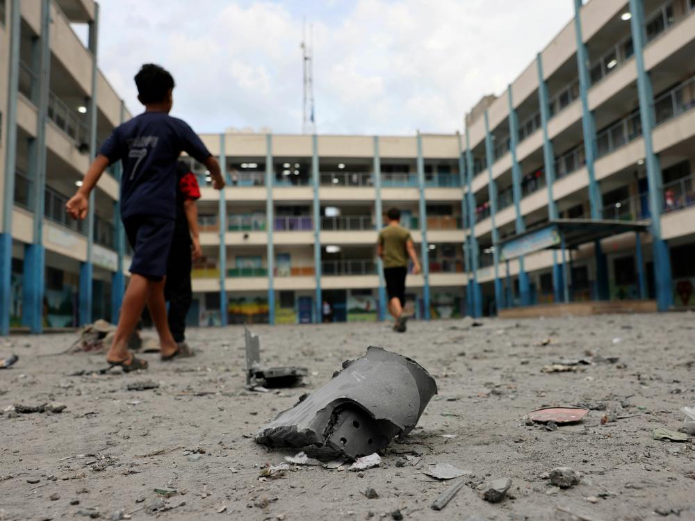 Palestinian children walk past debris in the courtyard of a school run by the United Nations Relief and Works Agency for Palestine refugees following Israeli airstrikes targeting Gaza City on Monday.