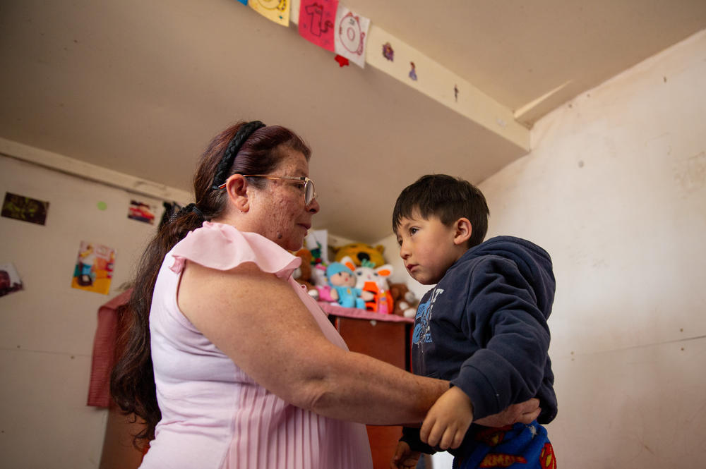 Salamanca helps her youngest grandson, Matías Lopez, 4, get dressed. She lives in a multi-generational home with her children and seven of her eight grandchildren in San Cristobal.