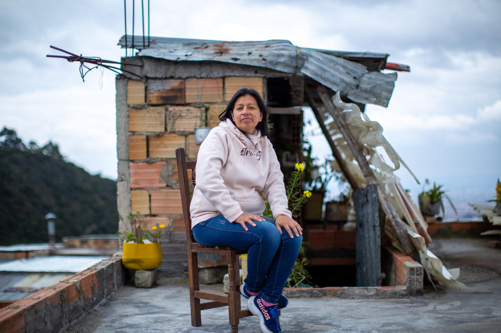 Infante, sitting for a portrait on her rooftop, lives with her three kids, her parents, sister and niece in a narrow, two-story concrete home overlooking the Andes mountains in the San Cristobal neighborhood of Bogotá. She says her caregiving work starts at 5 a.m. and doesn't stop until the kids are asleep.