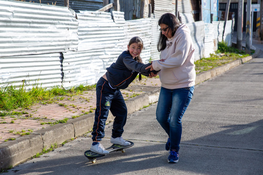 Infante plays with her youngest daughter, Brigitte, in front of their home in San Cristobal.