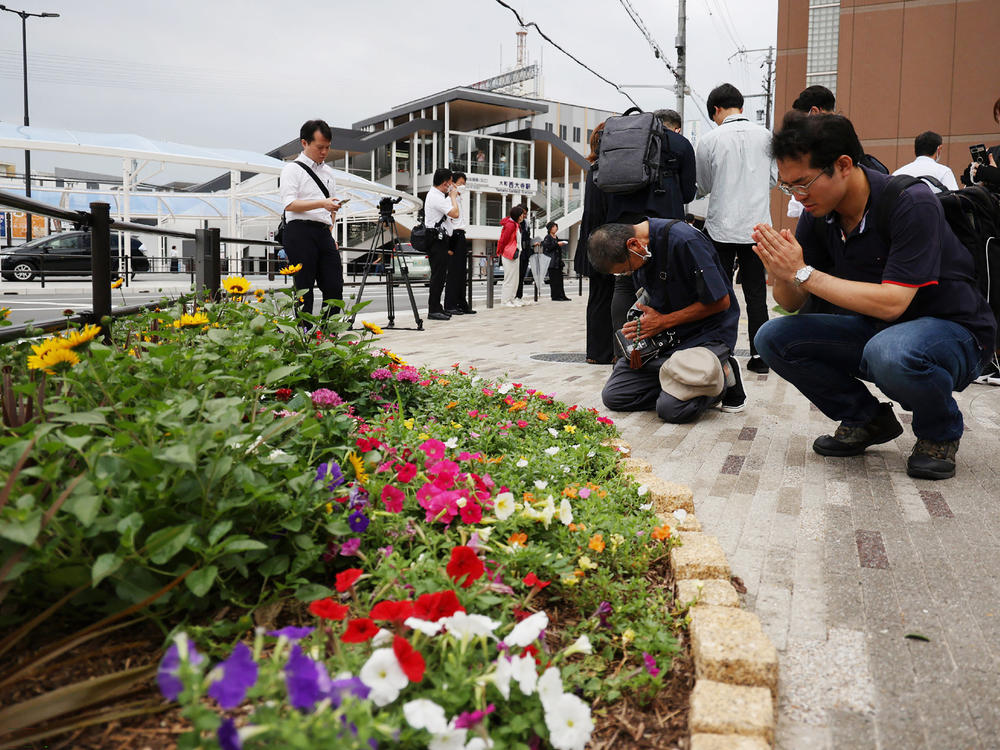 People pray outside Yamato-Saidaiji Station, where former Japanese Prime Minister Shinzo Abe was shot, on his first death anniversary of his death in Nara city on July 8.