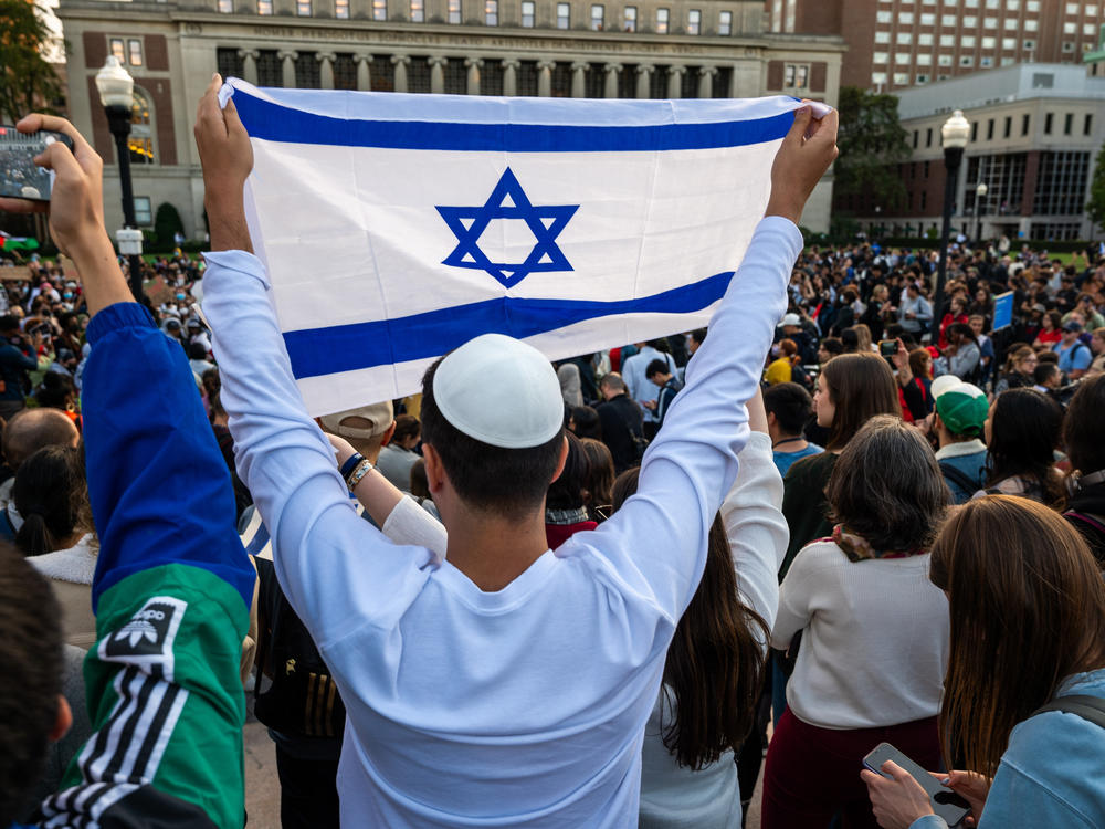 A man holds up an Israeli flag overlooking a pro-Gaza rally at Columbia University on Thursday.