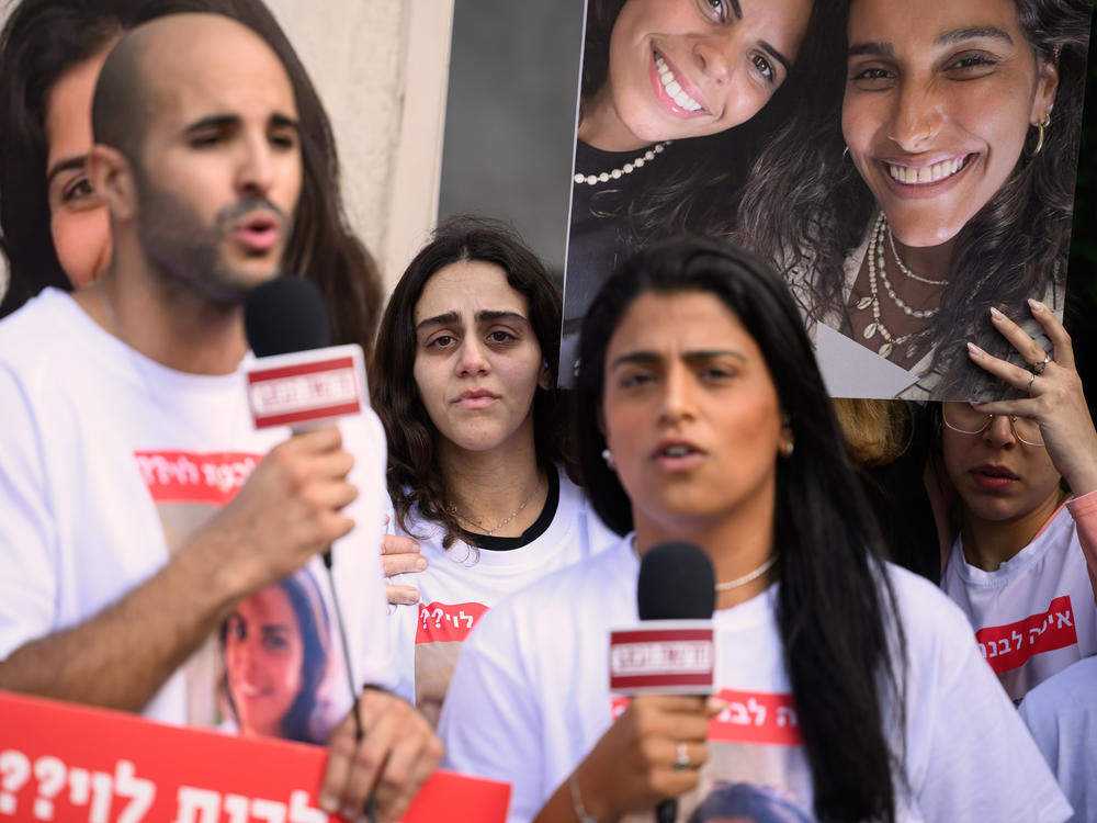 Family and friends of Livnat Levi, who was taken hostage by Hamas during an attack on Israel, hold up large photos of her as they are interviewed ahead of a press conference on Friday in Tel Aviv, Israel.
