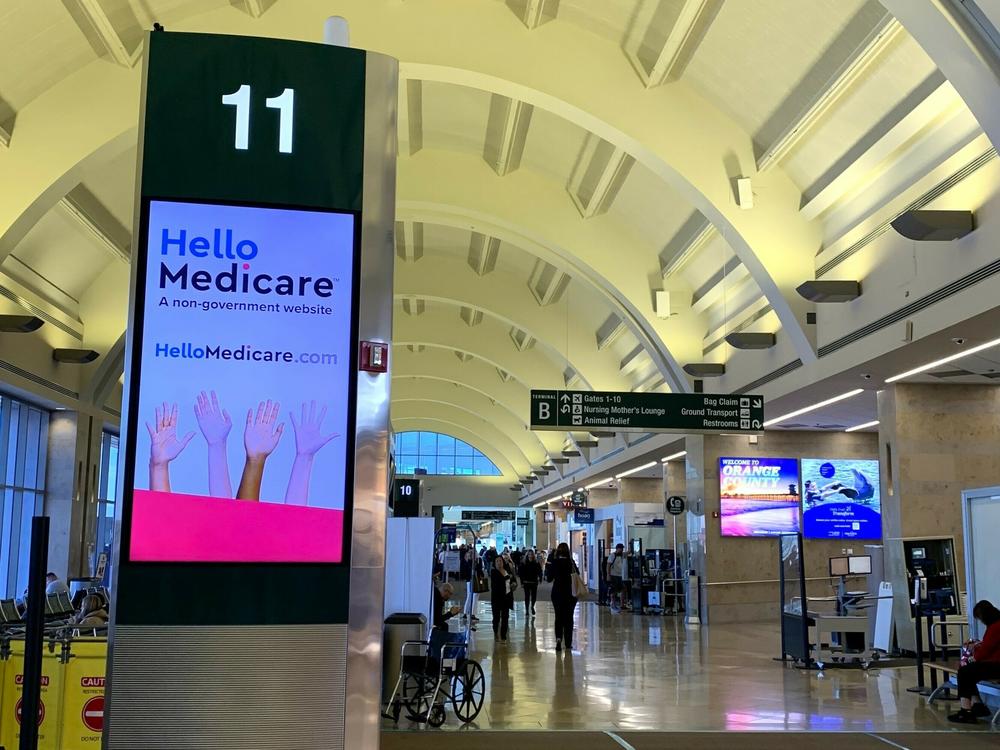 Open enrollment for Medicare begins Sunday and ads like this billboard inside California's John Wayne Airport are popping up. Marketing of Medicare plans is subject to new, stricter federal regulations this year.