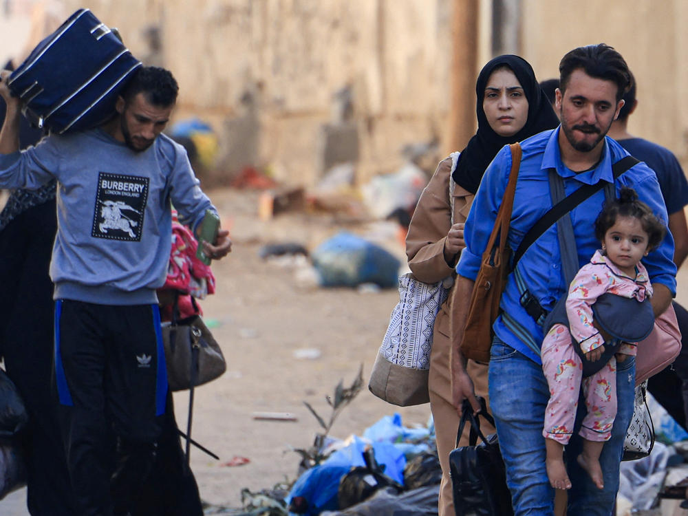 Palestinians with their belongings flee from their homes following Israeli airstrikes in Gaza City on Friday.