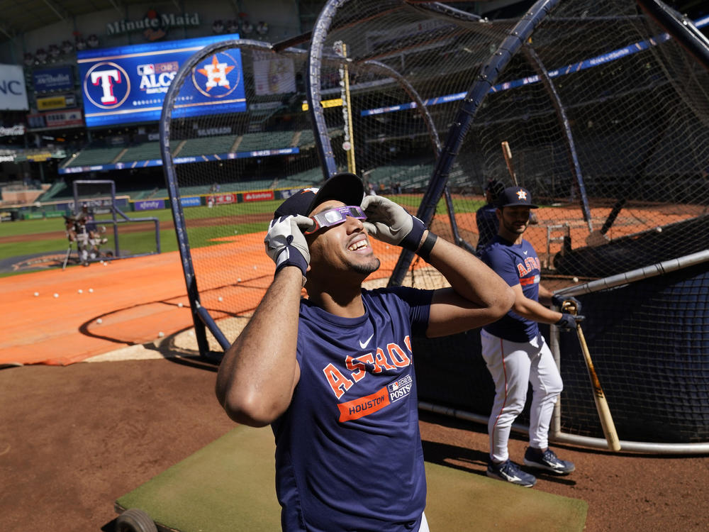 The Houston Astros' Dixon Machado wears protective glasses to view the solar eclipse during baseball practice in Houston on Saturday.