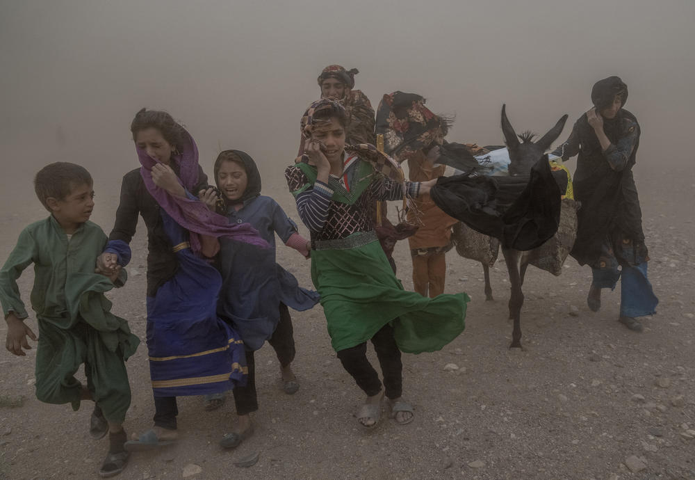Thurs., Oct. 12: Afghan girls and women carry donated aid to their tents, while they are scared and crying from the fierce sandstorm, after an earthquake in Zenda Jan district in Herat.