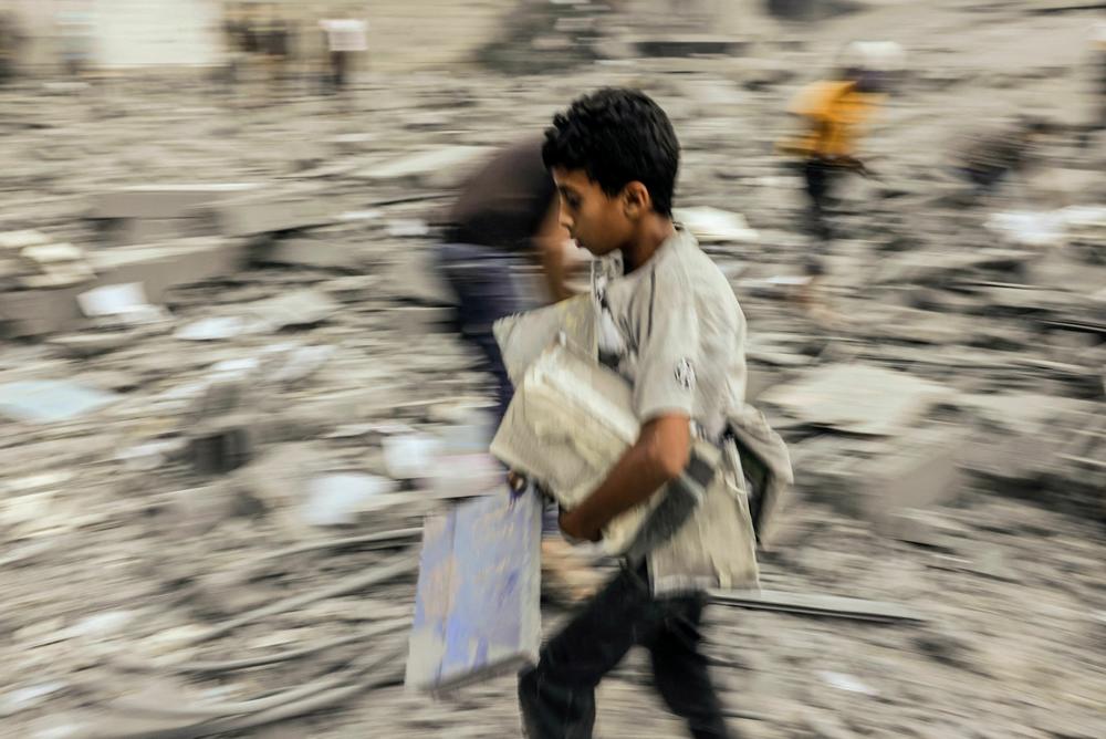 Sun., Oct. 15: A child walks away with belongings salvaged from the rubble of a building hit in an Israeli strike on Rafah in the southern Gaza Strip.