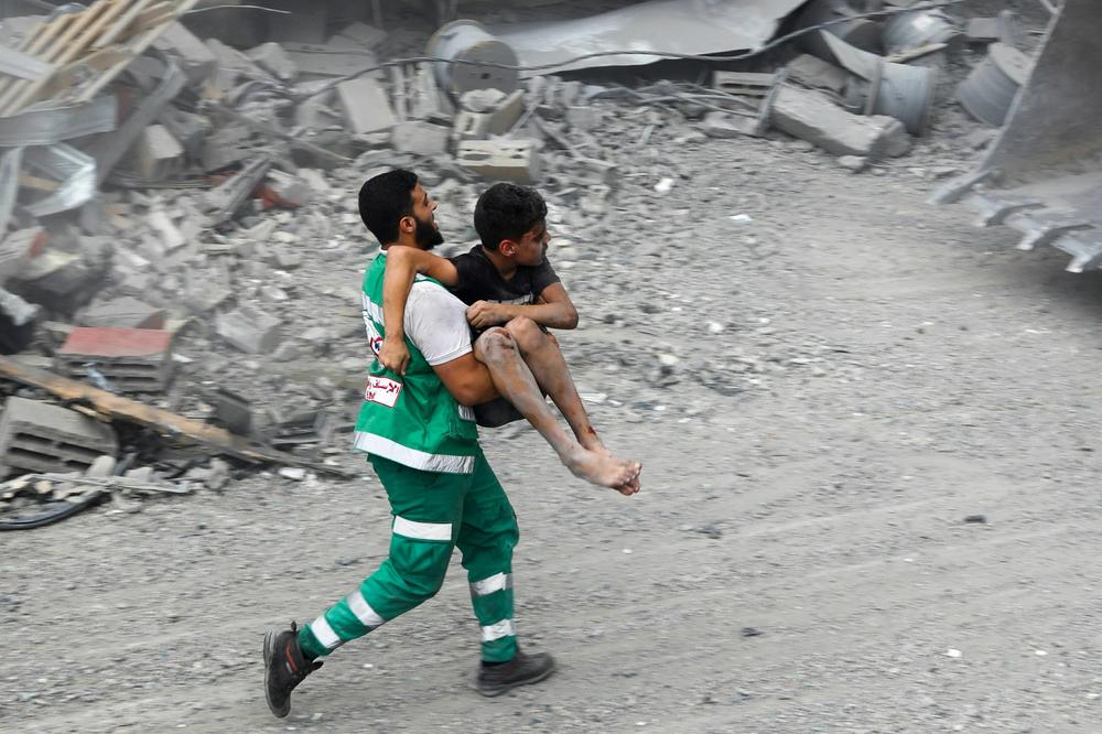 A member of the Palestinian Civil Defence carries a wounded boy rescued from the rubble of a home that was destroyed in an Israeli airstrike on October 9.
