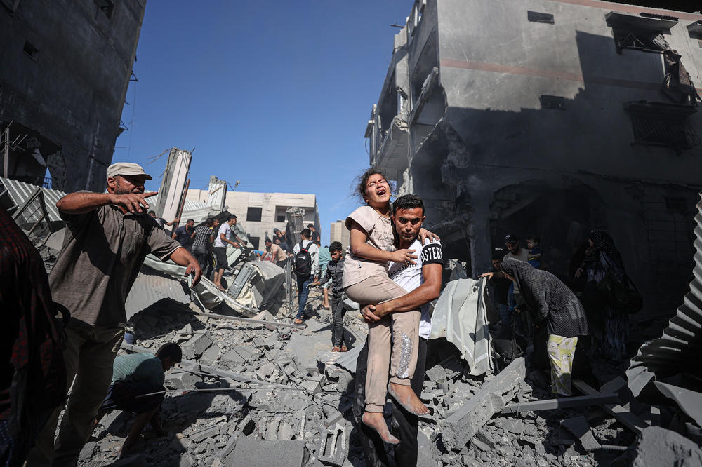 Civil defense teams and residents carry injured people as they launch a search and rescue operation around the buildings that were destroyed after Israel's attacks on the Gaza Strip, in Khan Younis, Gaza, Tuesday.