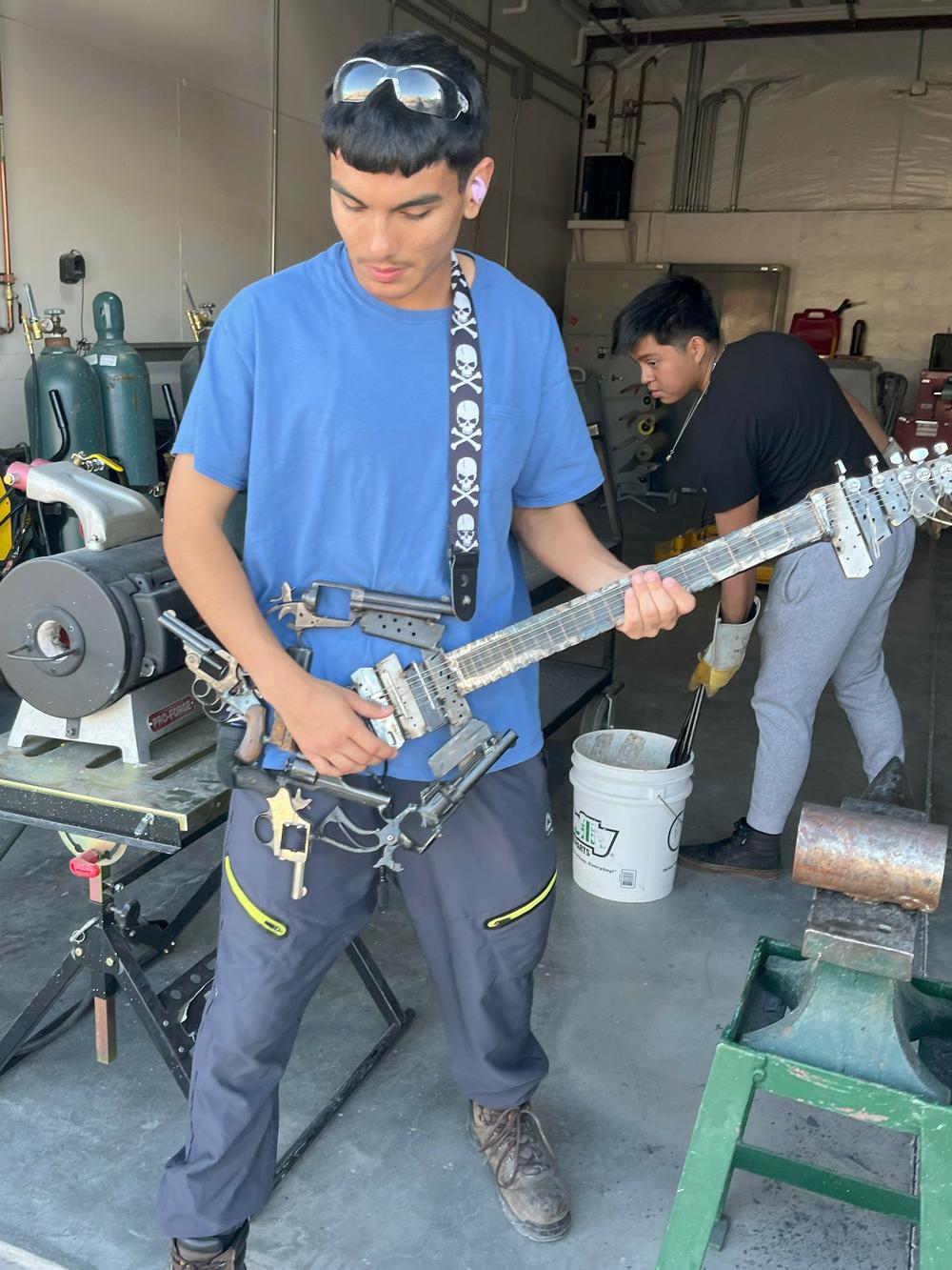 Nathan Alvarez, 18, shows off a functioning guitar that students at an after-class program at RFK Charter School in Albuquerque, N.M., welded together out of old guns.