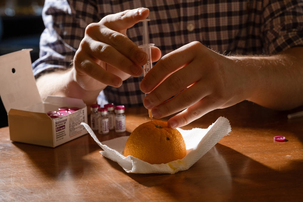 Riley Sullivan injects a dose of naloxone into an orange at his off-campus apartment.