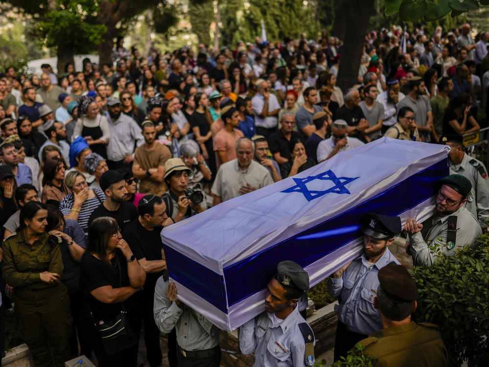 Israeli soldiers carry the flag-covered coffin of a person killed in the Hamas attack earlier this month. Rabbis and reservists have worked around the clock at a military base in Israel to identify and count the dead.