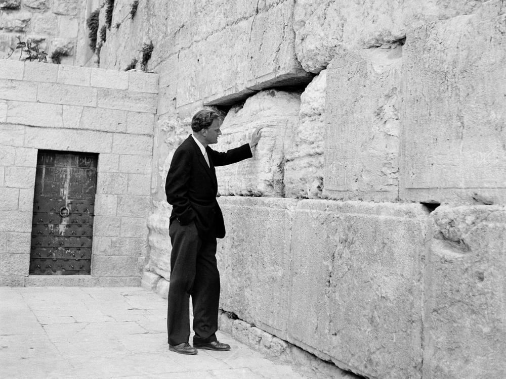 Evangelist Billy Graham stands by the Western Wall in Jerusalem on March 17, 1960. Graham went on an 18,000-mile preaching tour of Africa and the Middle East and this trip to Israel largely signaled a shift for evangelicals in their views of the country.