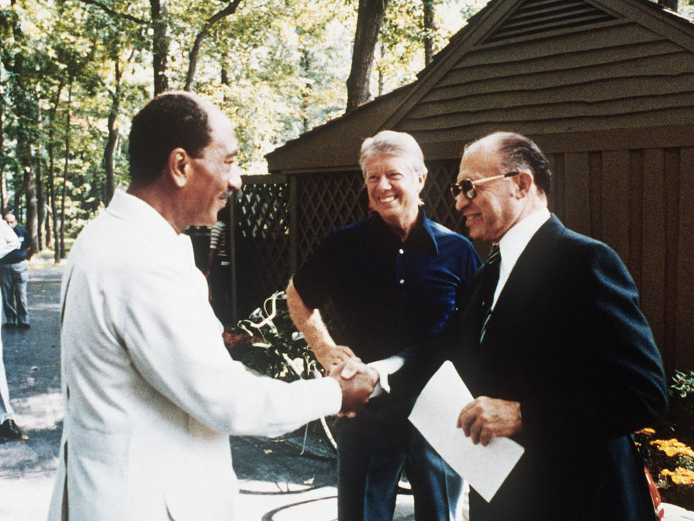 Egyptian President Anwar Sadat, left, shakes hands with Israeli Premier Menachem Begin, as U.S. President Jimmy Carter looks on, Sept. 6, 1977, at Camp David.