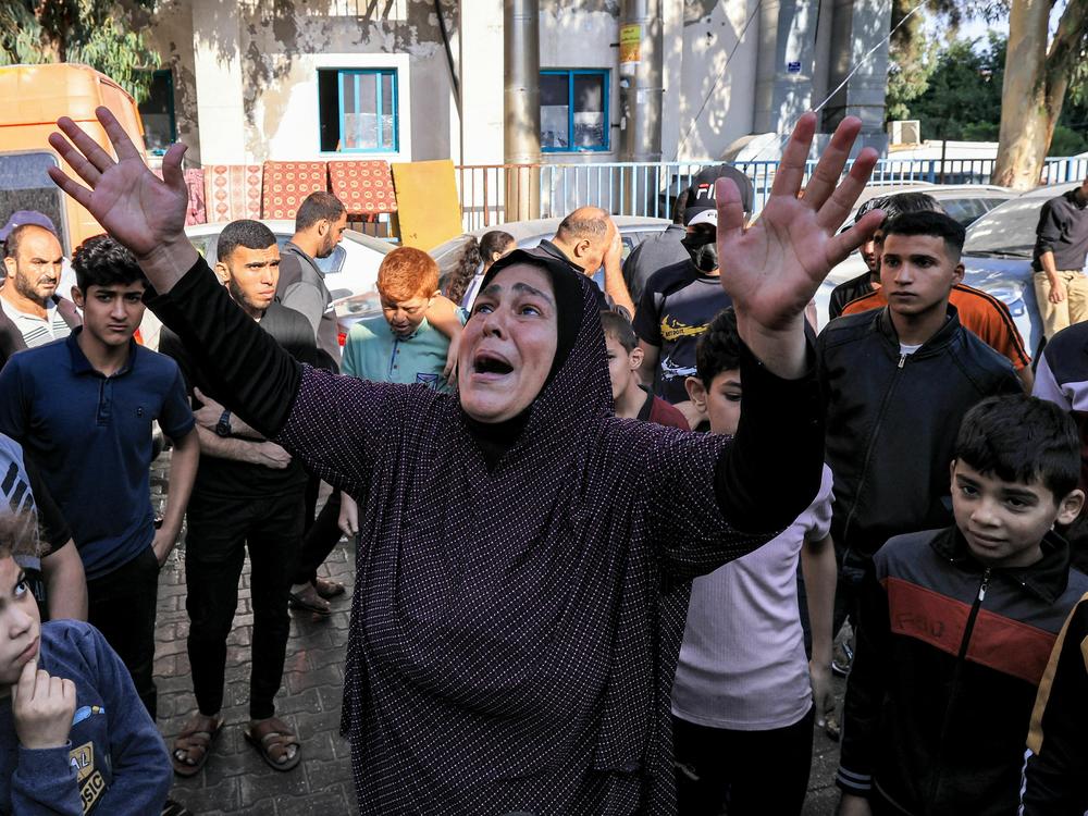 A woman reacts as people gather at the site of Al Ahli Arab hospital in central Gaza on Wednesday in the aftermath of an overnight explosion there.